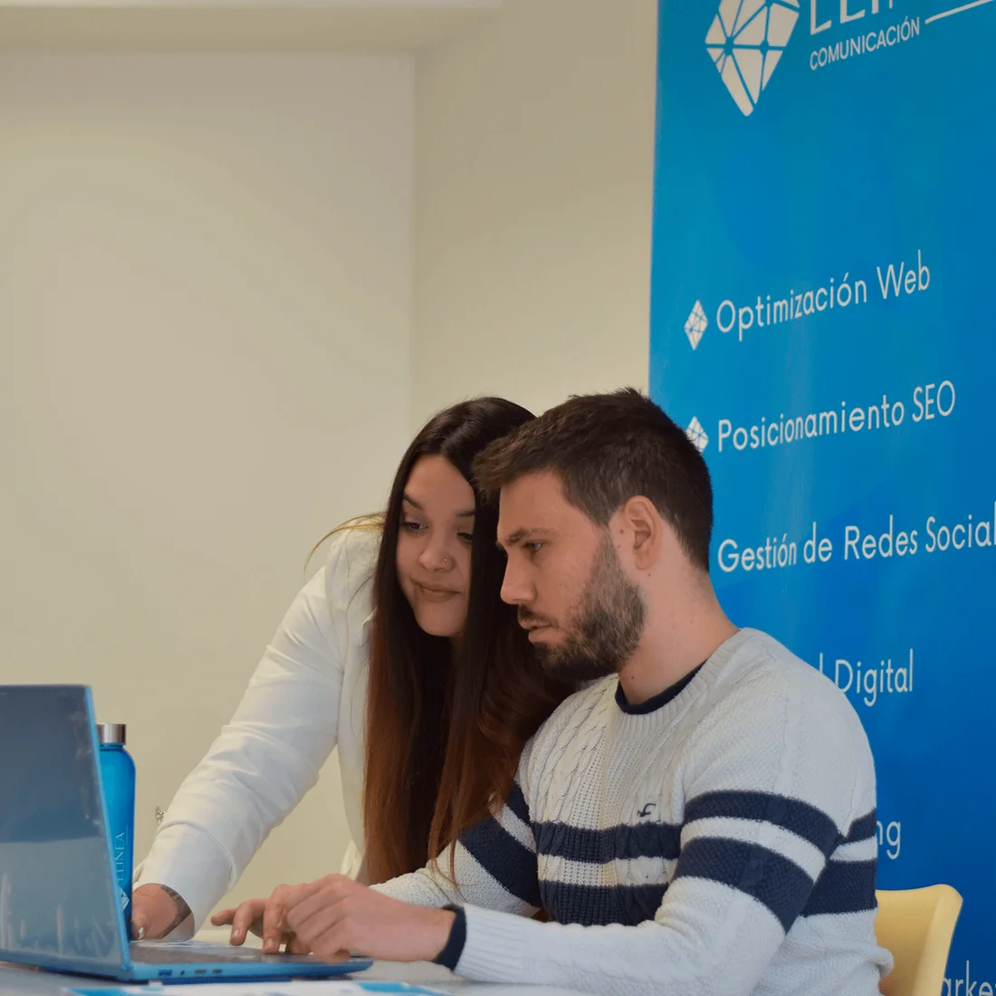 Colaboración sobre un portátil junto a la identidad de Elinea Comunicación